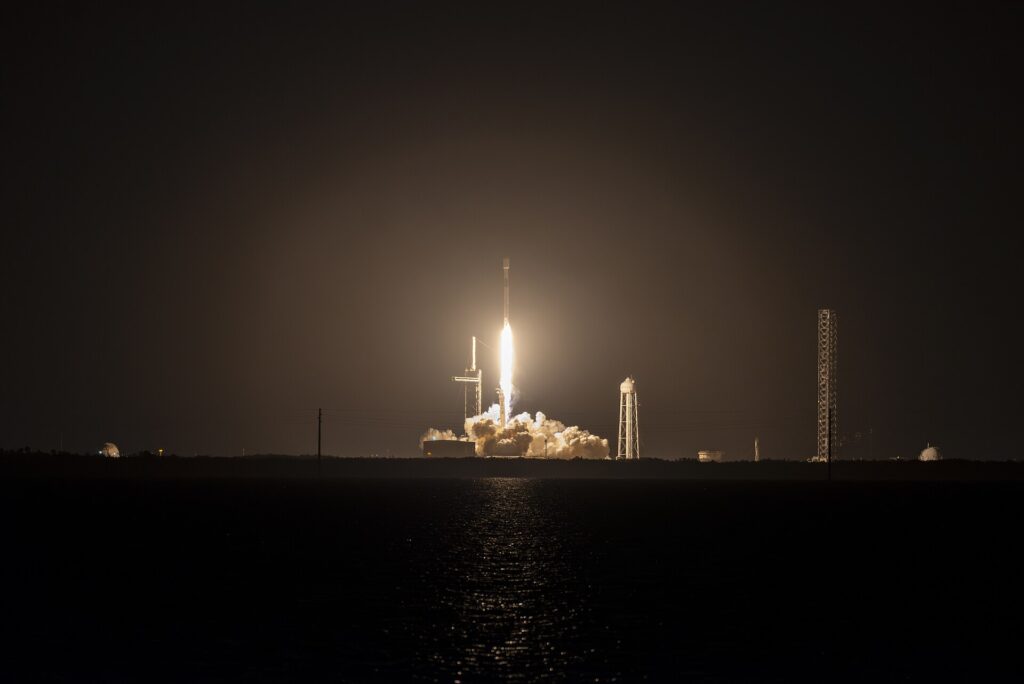 Juice spacecraft flying past Earth in a low orbit with Earth and Moon in the background